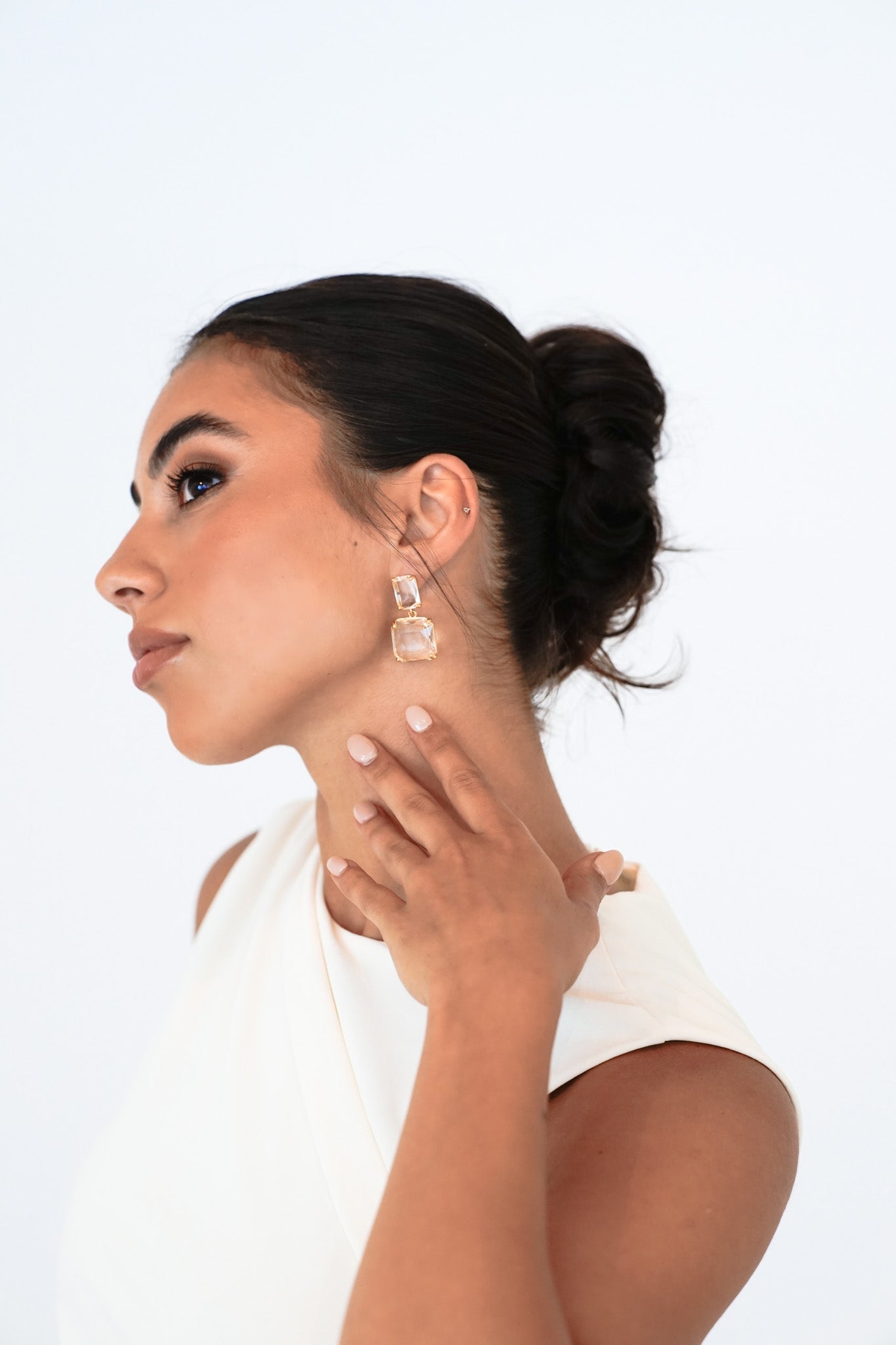 Bridal portrait with dark brunette updo – bride holding neck to showcase Bianca Earrings towards camera