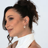 Bride in updo wearing Loretta Earrings – pensive gaze off-camera with gloved hand resting on shoulder
