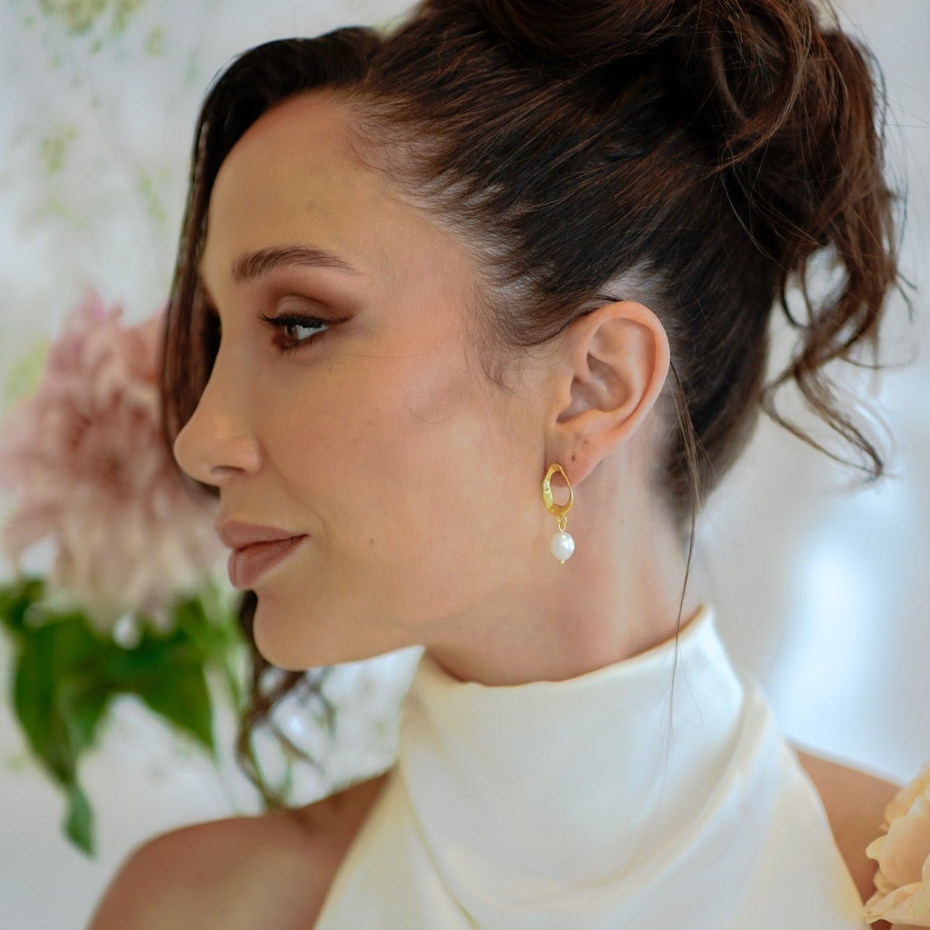 Model in white halter dress wearing gold pearl drop earrings from The Sophia Set