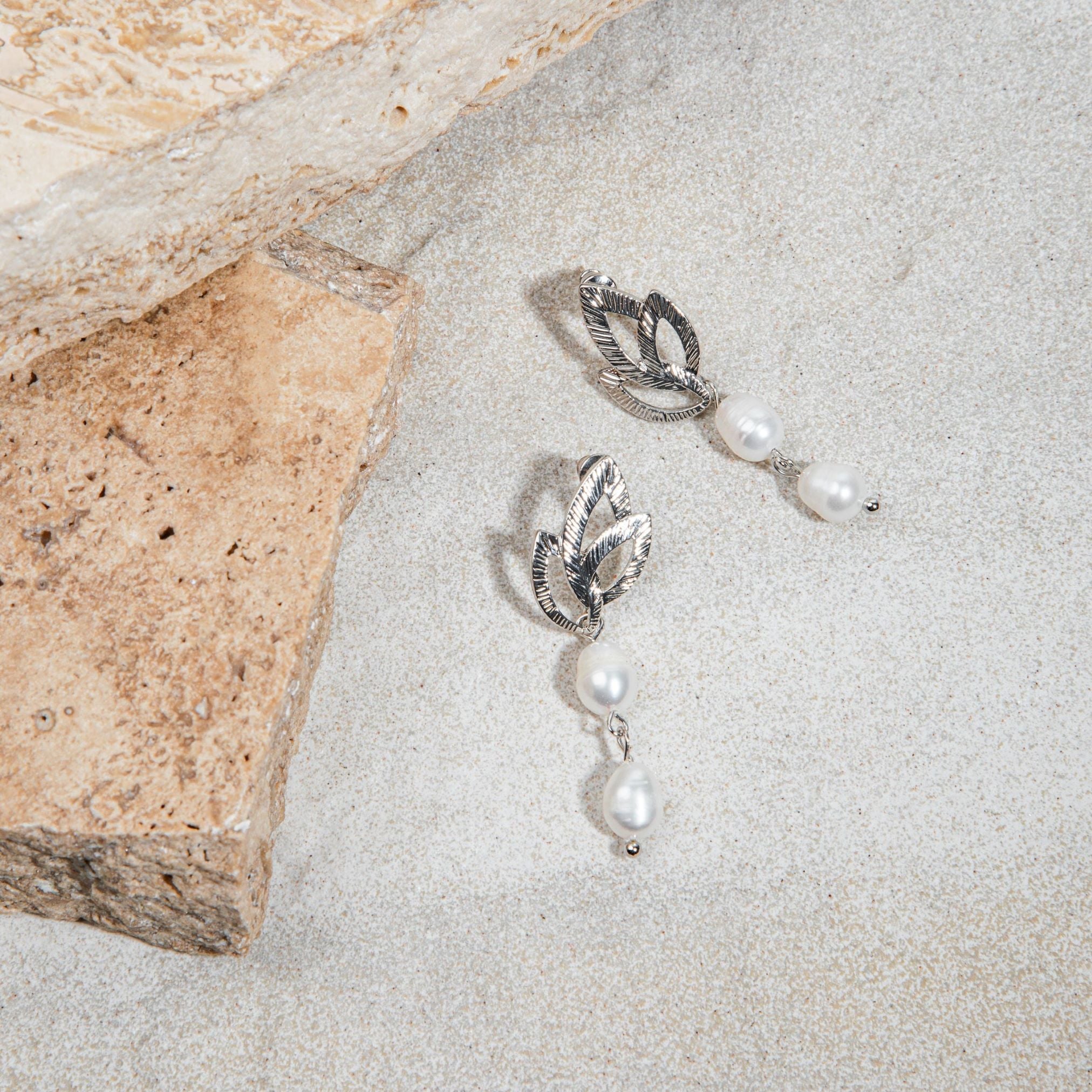 Silver Tiffany Earrings flatlay on soft grey sand-toned background – shown beside a sandstone paver, highlighting the layered pearl drop and stylised stud design