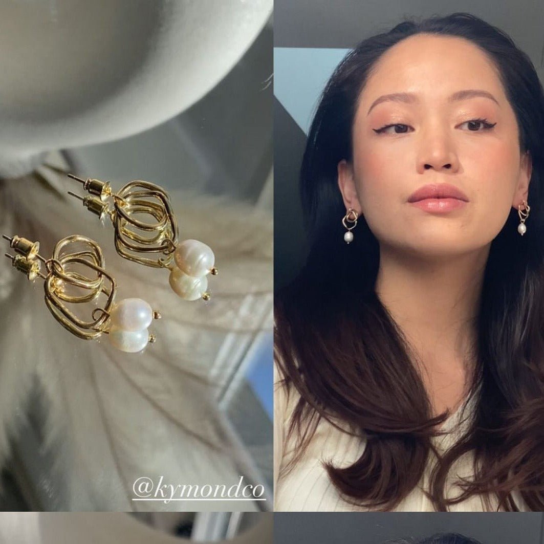 Isabella Earrings – gold hoop pearl earrings on glass table and worn in mirror selfie by woman with dark flowing hair and natural makeup