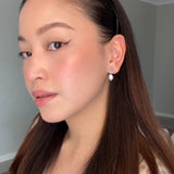 Woman wearing Peyton Earrings in silver – soft makeup, straight brunette hair tucked behind ears, close-up selfie