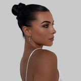 Woman wearing Leah Earrings in profile – black hair in sleek bun, white outfit, confident expression and pearl drop visible against clean skin