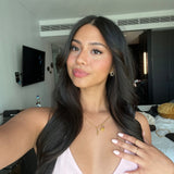 Woman with long black hair wearing Dainty Flower Earrings in hotel room mirror selfie – clothing and jewellery on unmade bed in background