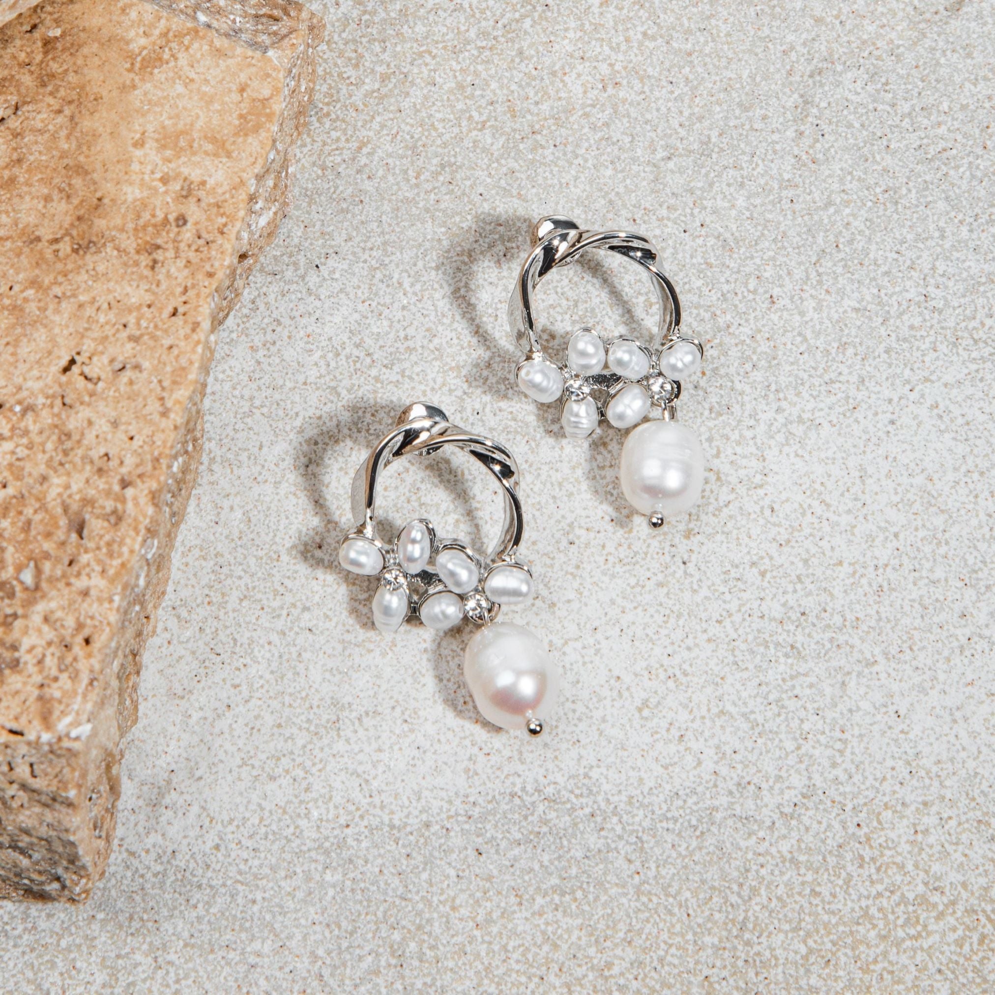 Jayda Earrings in silver – styled flatlay on sand with sandstone paver background