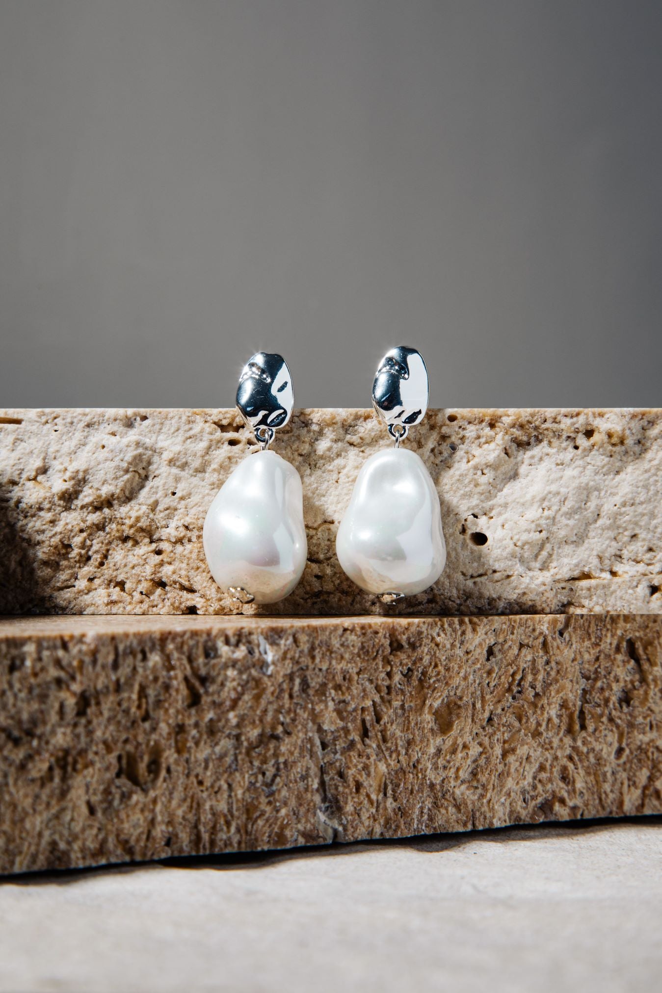 Kat Earrings – freshwater pearl drop earrings in silver on stacked brown pavers and grey background
