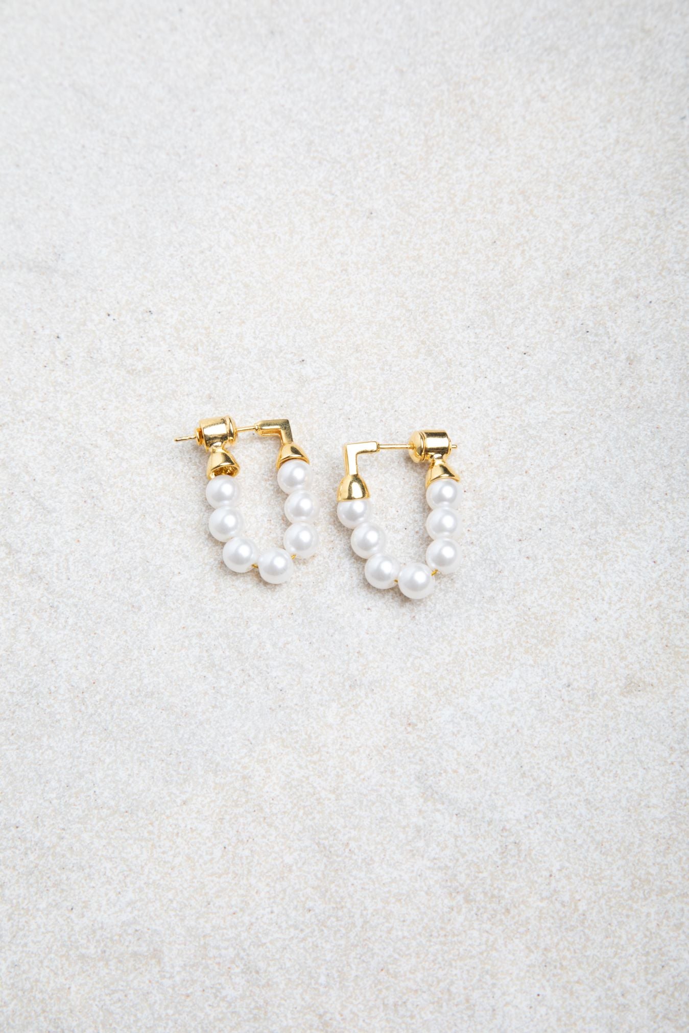 Kristy Earrings on textured felt background, softly lit to highlight pearl detail and gold stud