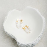 Kristy Earrings displayed in a smooth porcelain bowl with dimpled outer texture, set against a soft felt background in gentle light