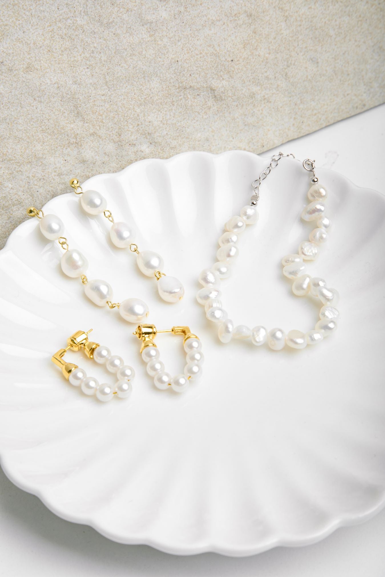 Kristy Earrings and matching pearl necklace displayed on a scalloped porcelain plate beside a similar earring style – showcasing a coordinated jewellery set
