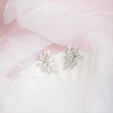 Kya Earrings in silver on a scalloped porcelain plate with soft pink glow and sheer veil in the background