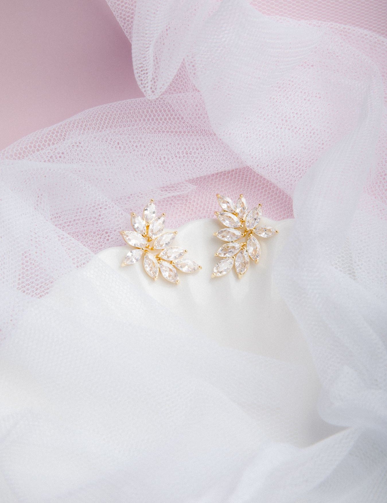 Kya Earrings in gold on a scalloped porcelain plate with soft pink glow and sheer veil in the background