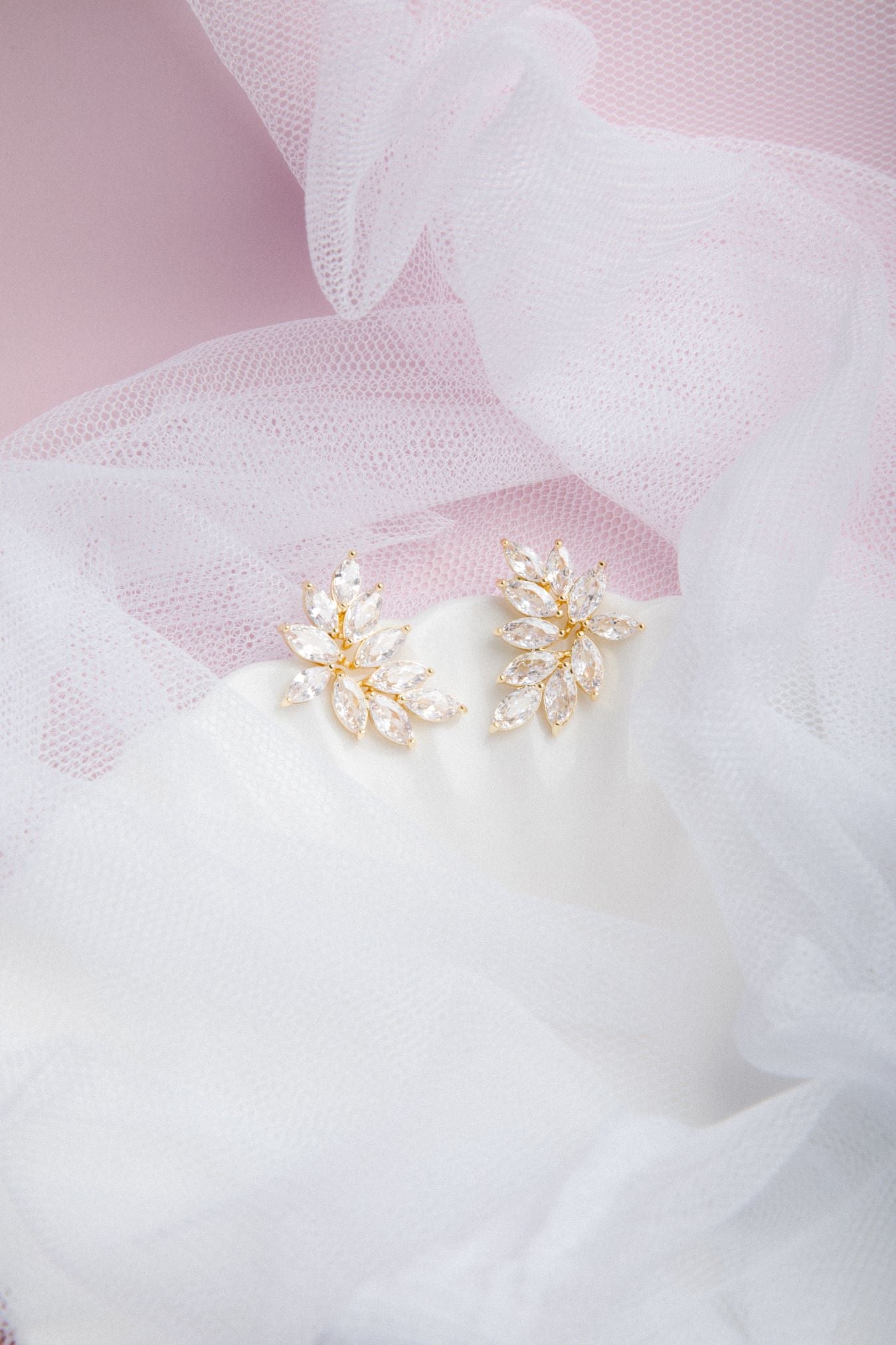 Kya Earrings in gold on a scalloped porcelain plate with soft pink glow and sheer veil in the background