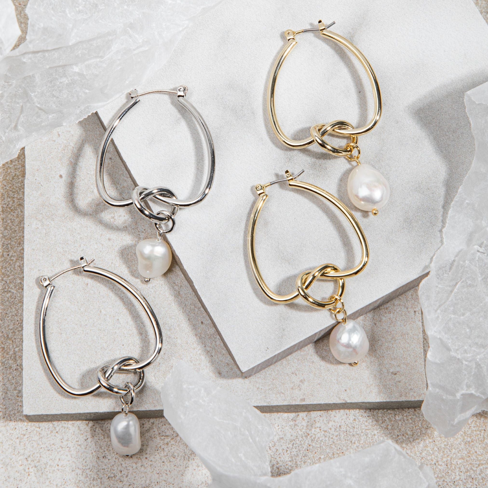Celeste Earrings – gold/silver knot and pearl drop earrings on white tile background