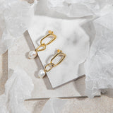 Sydney Earrings in gold – flatlay on marble tile with wrapping paper and mottled neutral floor background