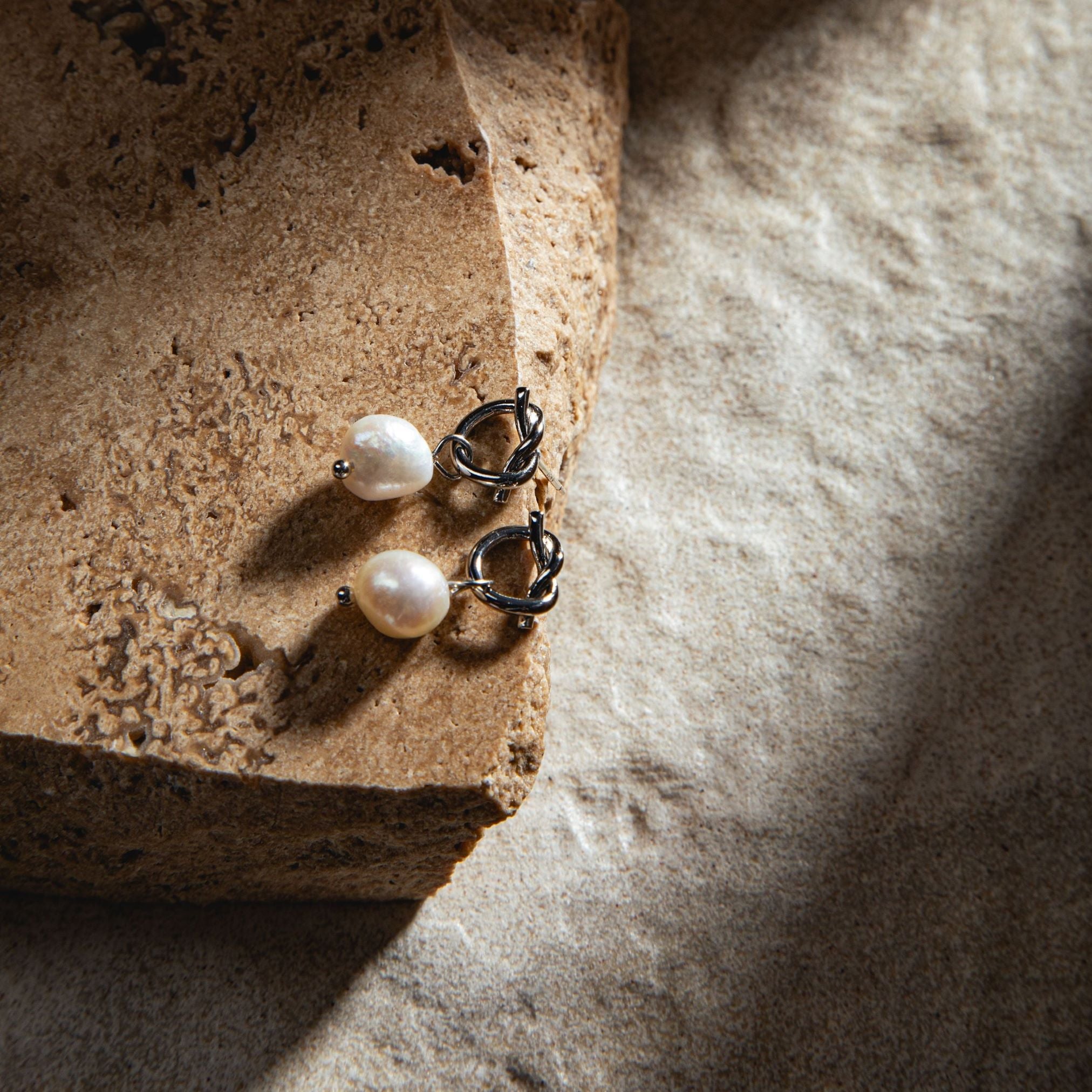 Peyton Earrings in silver – placed on a sandstone paver with dramatic lighting and a sand-toned textured backdrop