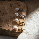 Savannah Earrings in gold and silver – flatlay on sandstone paver with dramatic lighting