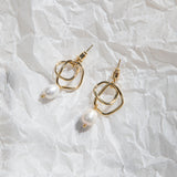 Isabella Earrings – gold twisted hoop earrings with floating pearl on crinkled translucent wrapping paper