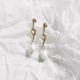 Crystal Earrings – gold knotted pearl drop earrings on crinkled translucent wrapping paper