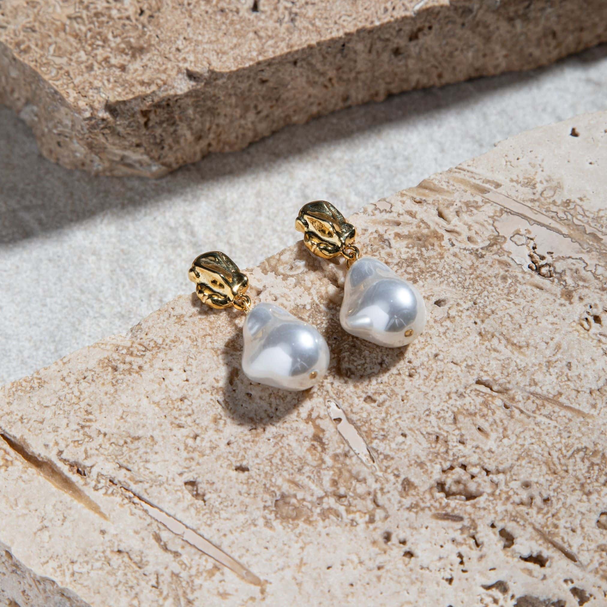 Kat Earrings – freshwater pearl drop earrings in gold on brown pavers and concrete background