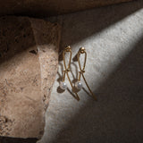Kiera Earrings on brown and white mottled surface beside a brown paver, illuminated by a dramatic ray of light