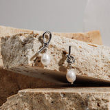Savannah Earrings in silver hanging from sandstone paver