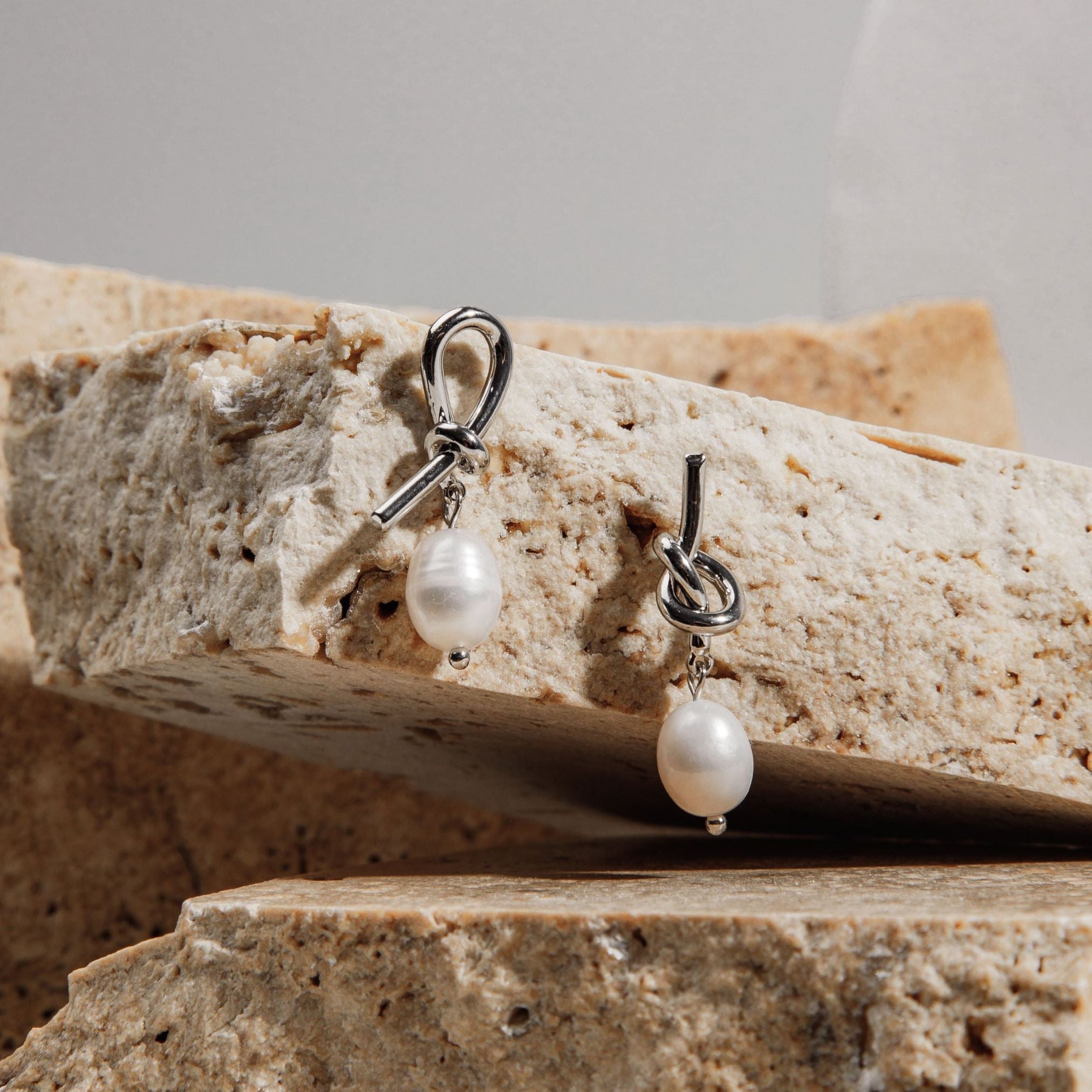 Savannah Earrings in silver hanging from sandstone paver