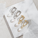 Sydney Earrings – gold and silver versions flatlay on marble tile with mottled grey-brown floor and surrounding wrapping paper