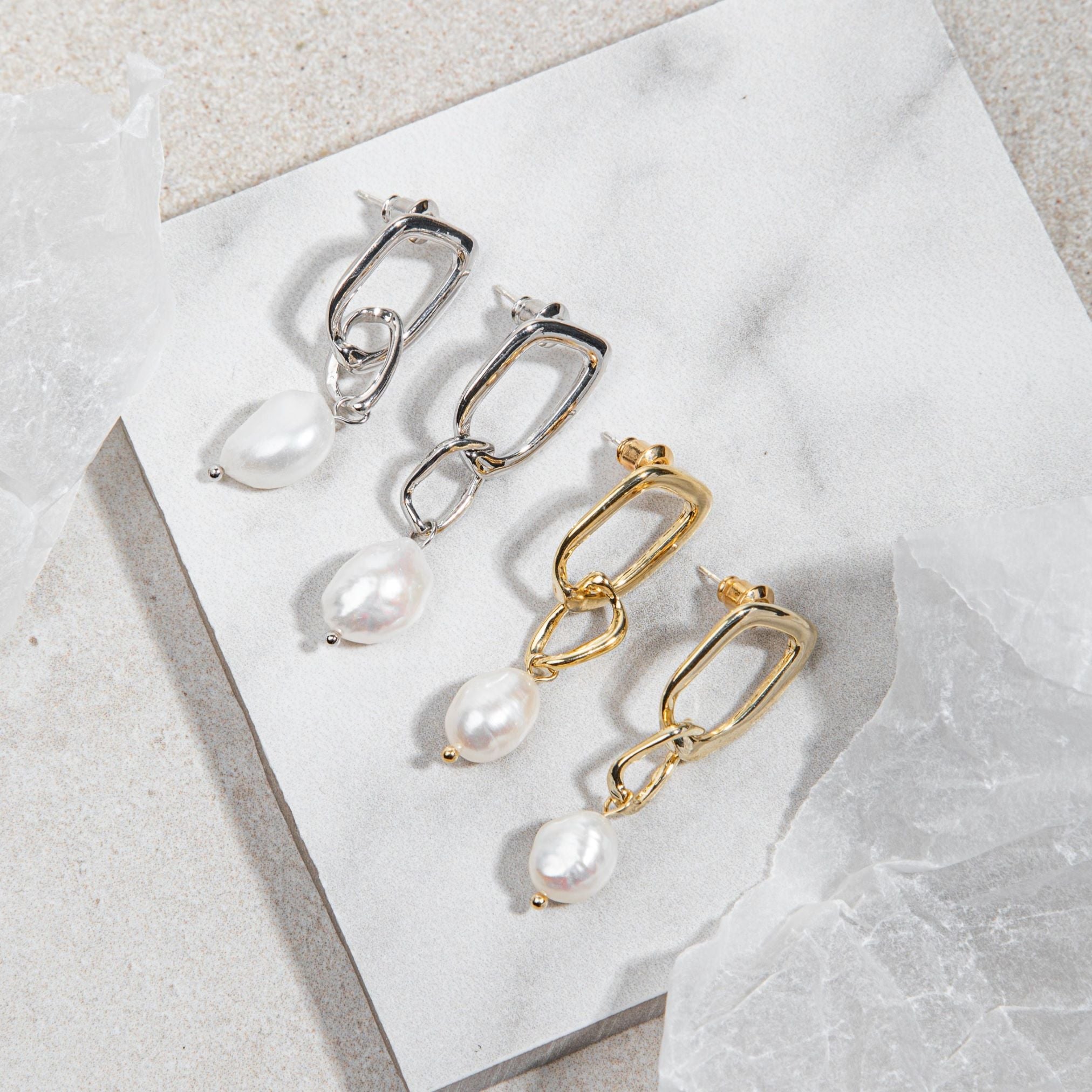 Sydney Earrings – gold and silver versions flatlay on marble tile with mottled grey-brown floor and surrounding wrapping paper