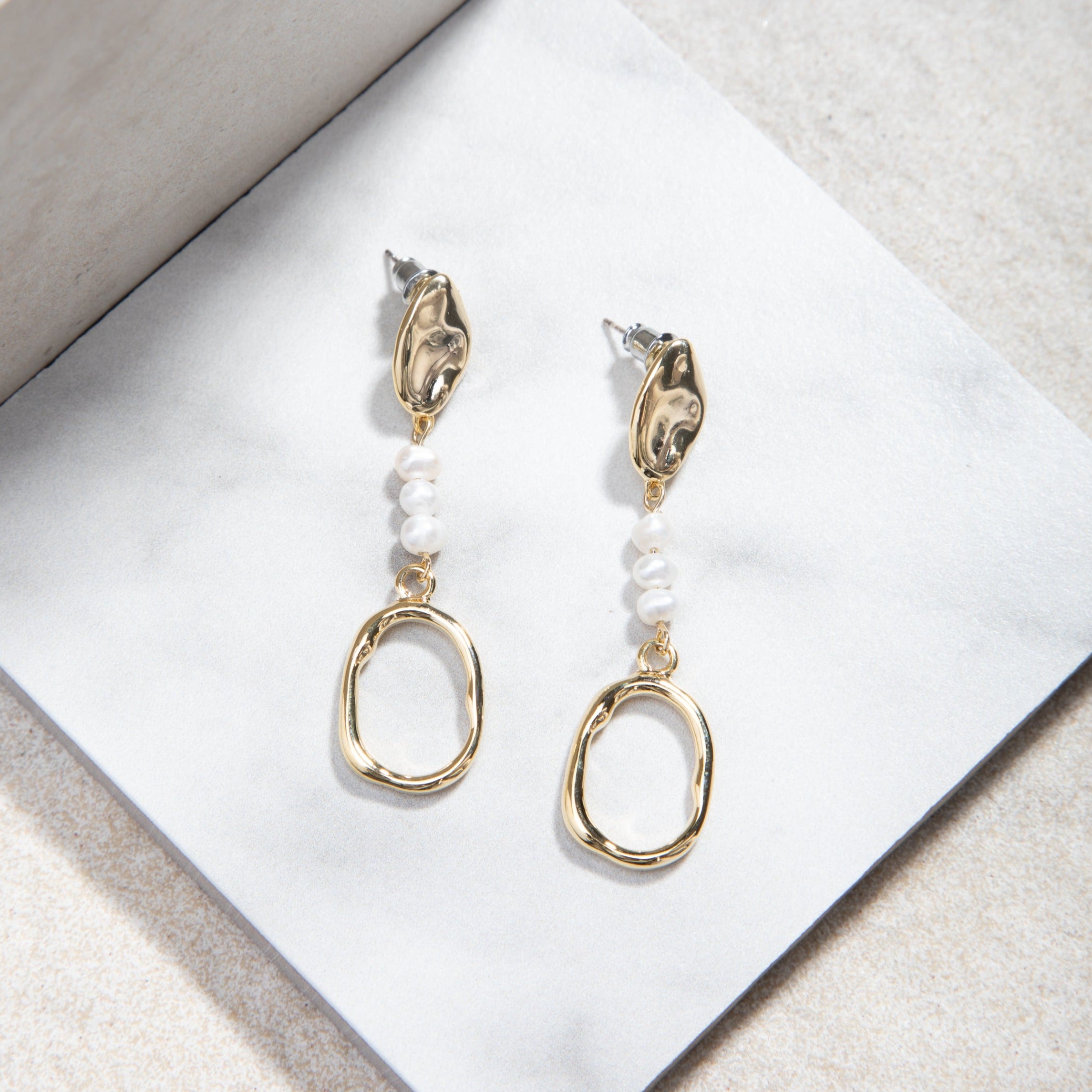 Tania Earrings displayed on a smooth white matte tile with a light brown mottled felt background