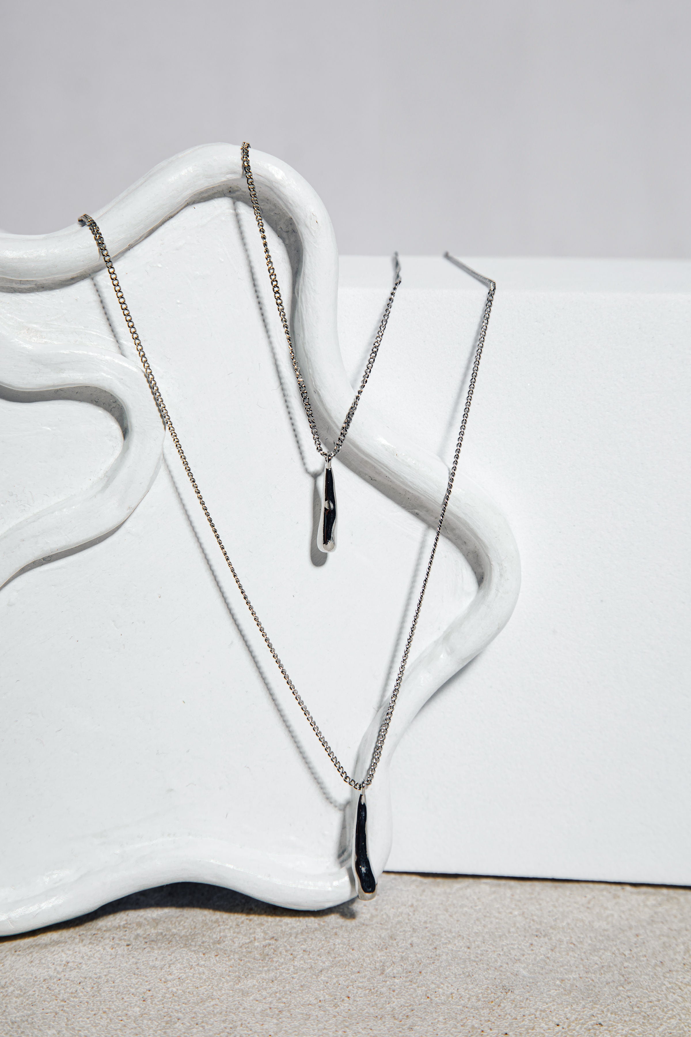 The Sophia Set necklace – molten-effect silver drop pendant on sculptural white background