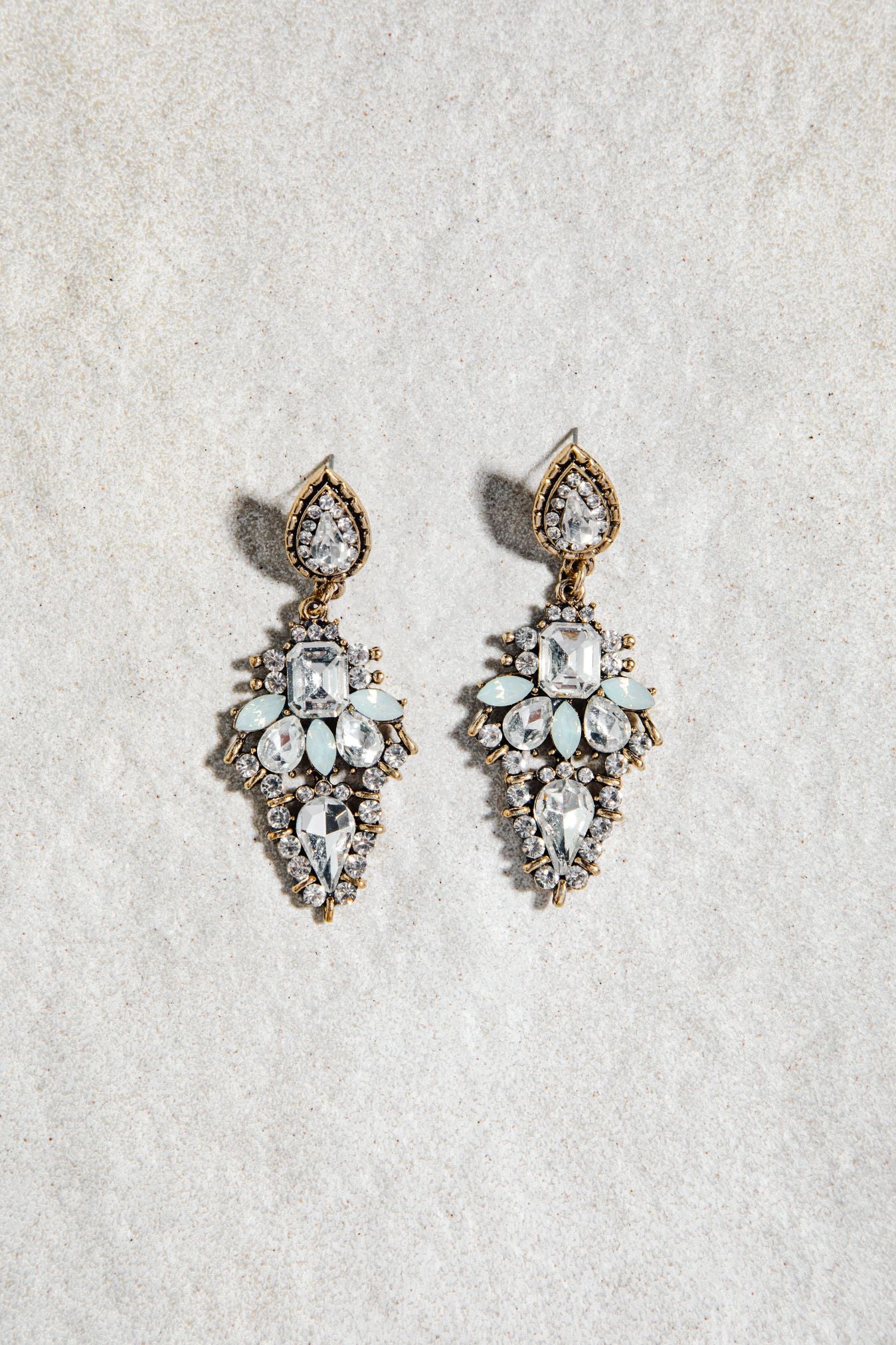 Alexia Earrings – prong-set vintage drop earrings in white and aqua colourway on white textured background