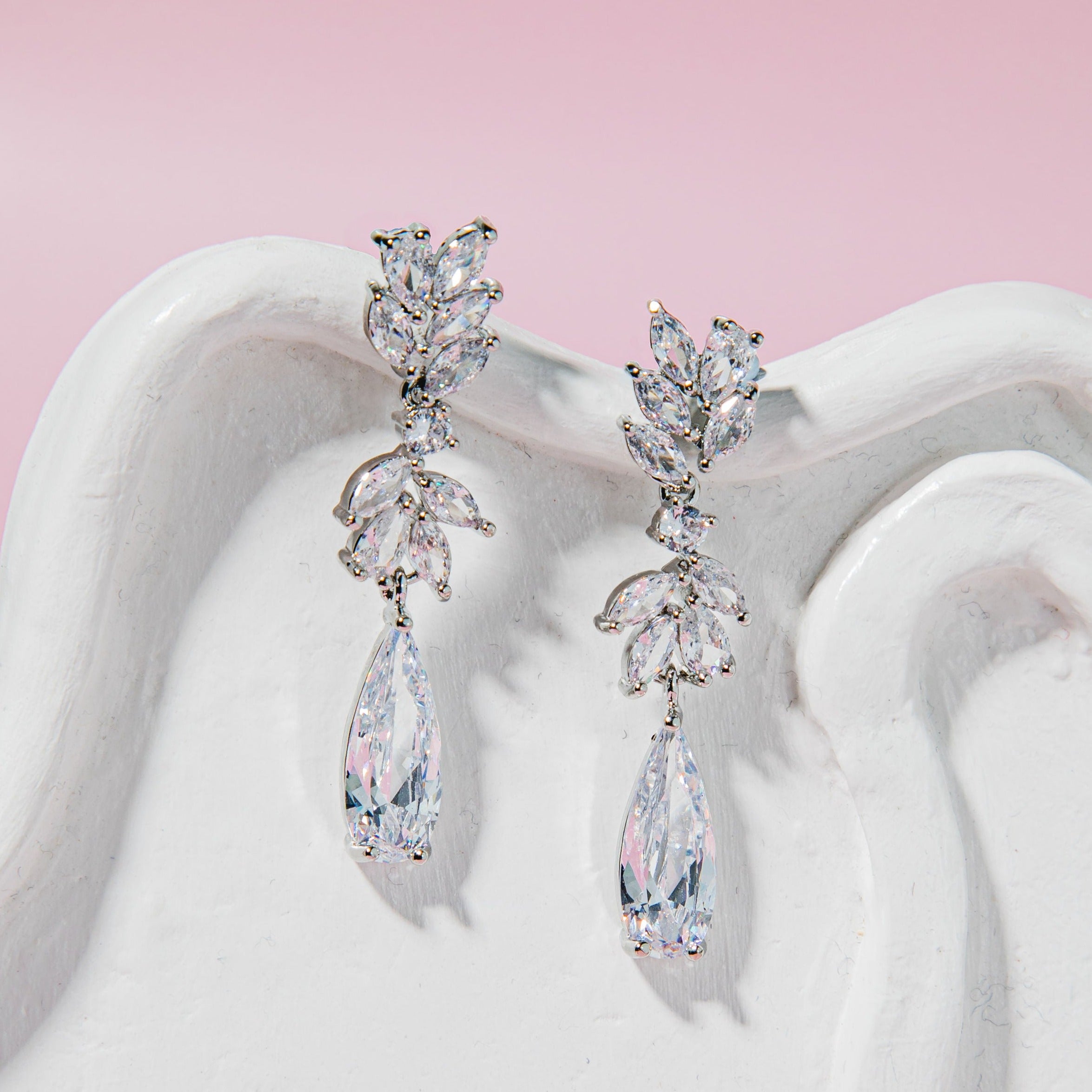 Stella Earrings – retro-inspired teardrop crystal earrings with rhinestone clusters on a textured stoneware plate with soft pink background