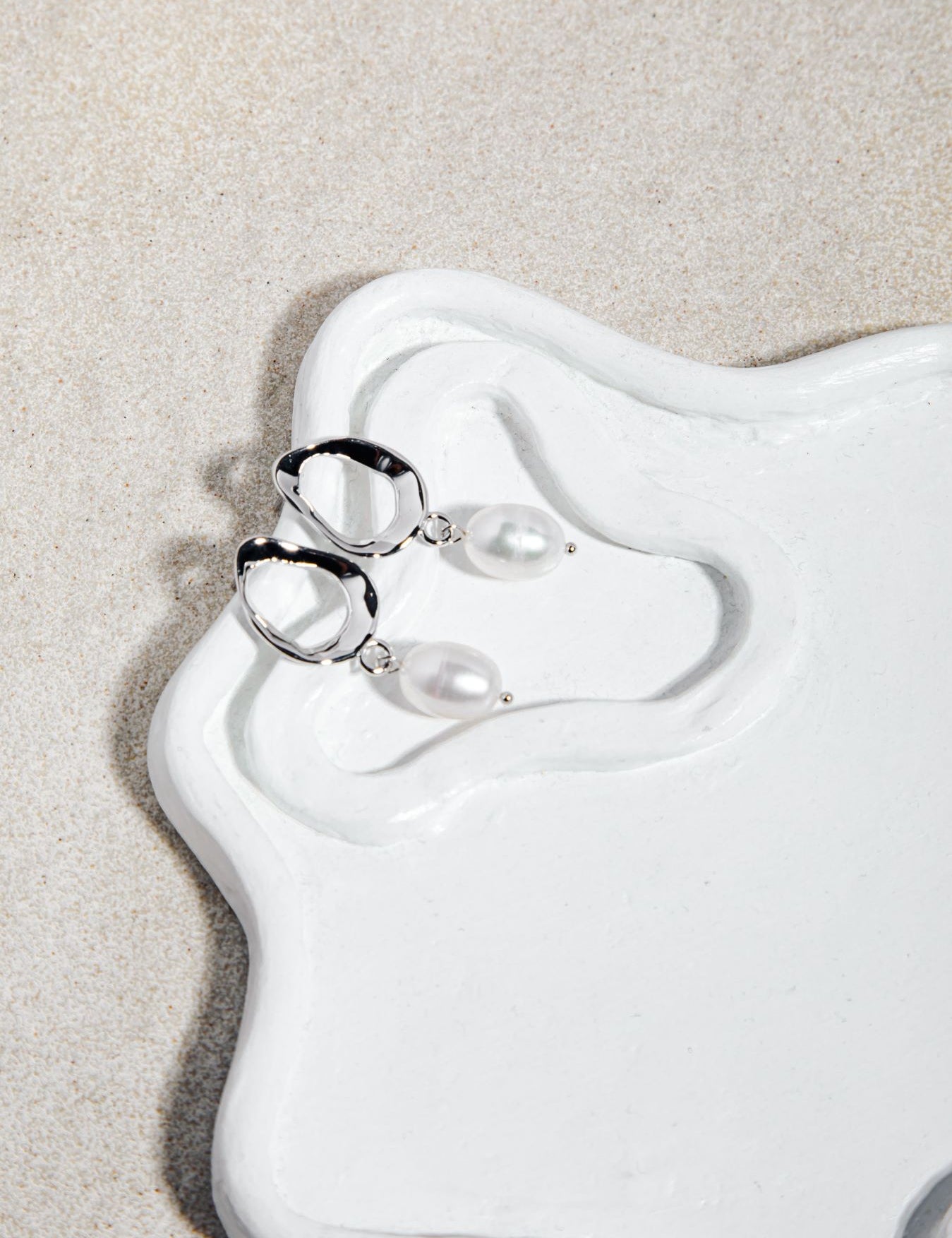 Silver pearl drop earrings from The Sophia Set styled on ceramic plate