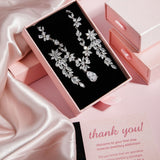 The Simone Set – platinum-plated floral necklace with teardrop cubic zirconia pendant in black velvet box, styled on pink satin background