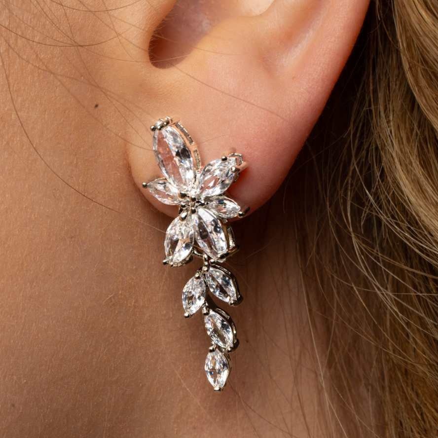 Close-up of Gemma Earrings in silver worn on ear – showing floral structure and prong-set crystal detailing.