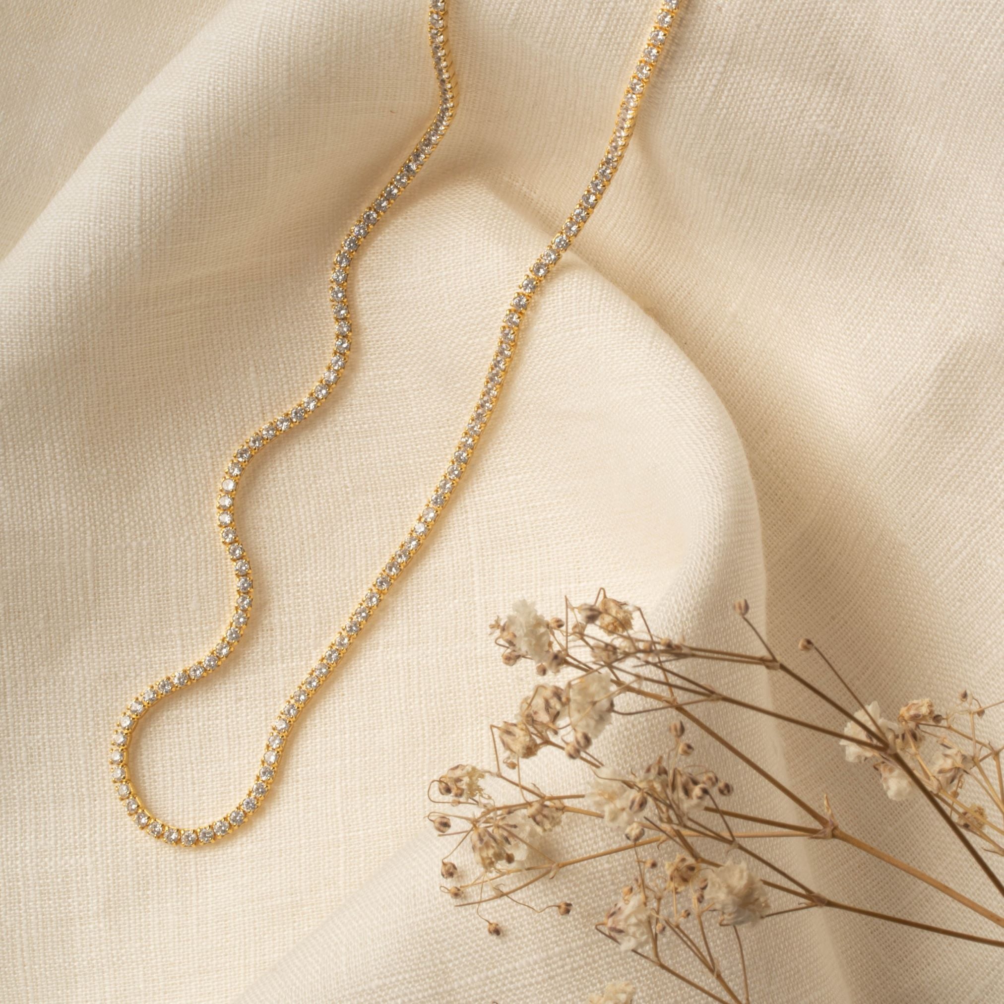 Classic Tennis Necklace in gold – flatlay on linen with dried flowers