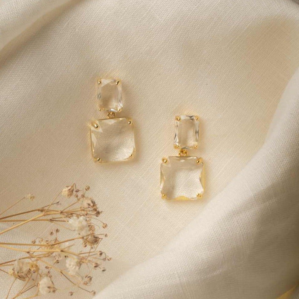 Bianca Earrings in gold – laid on linen cloth with dried flower beside, soft natural tones