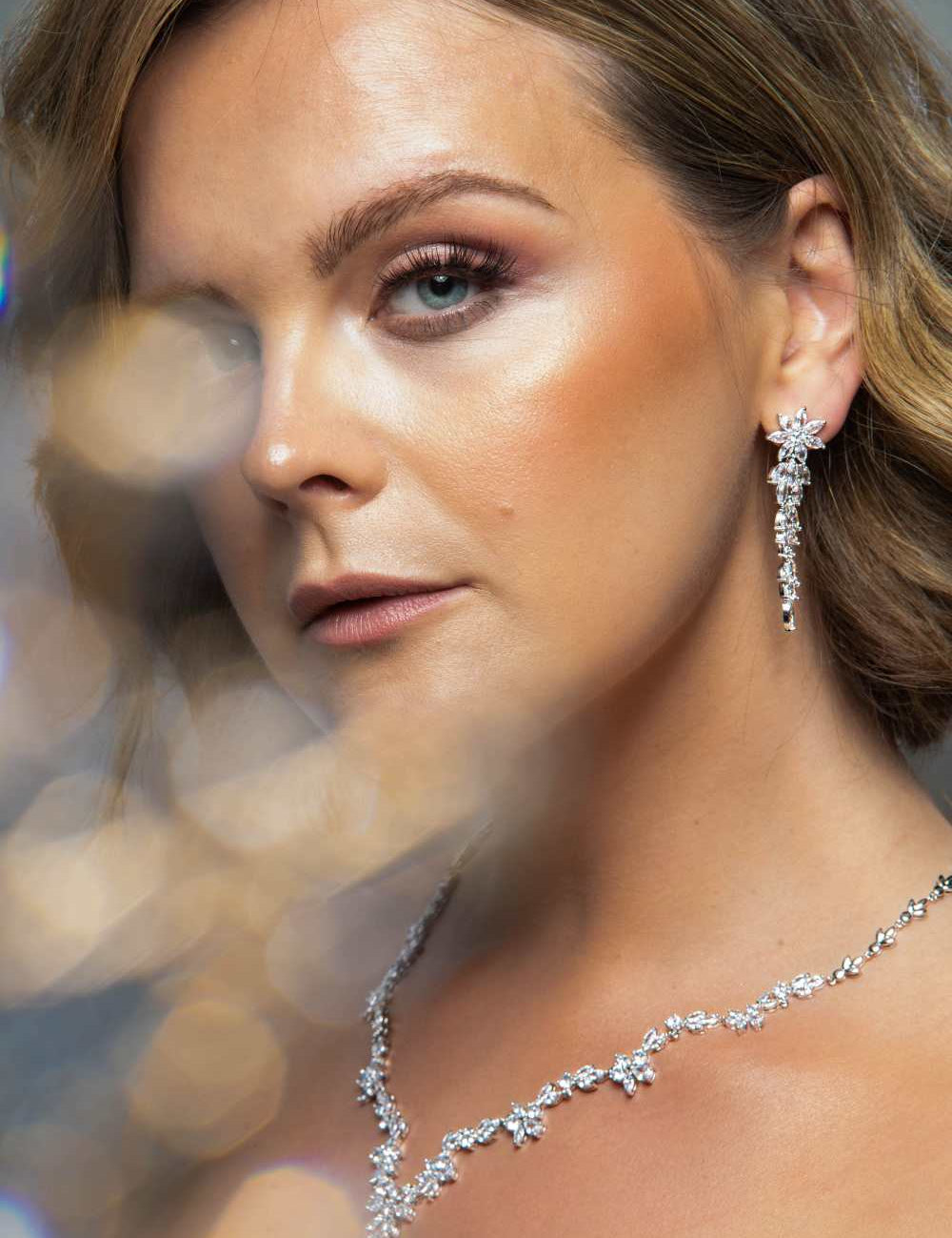Woman wearing The Simone Set – close-up of floral bridal earrings and necklace with marquise and round-cut cubic zirconia stones