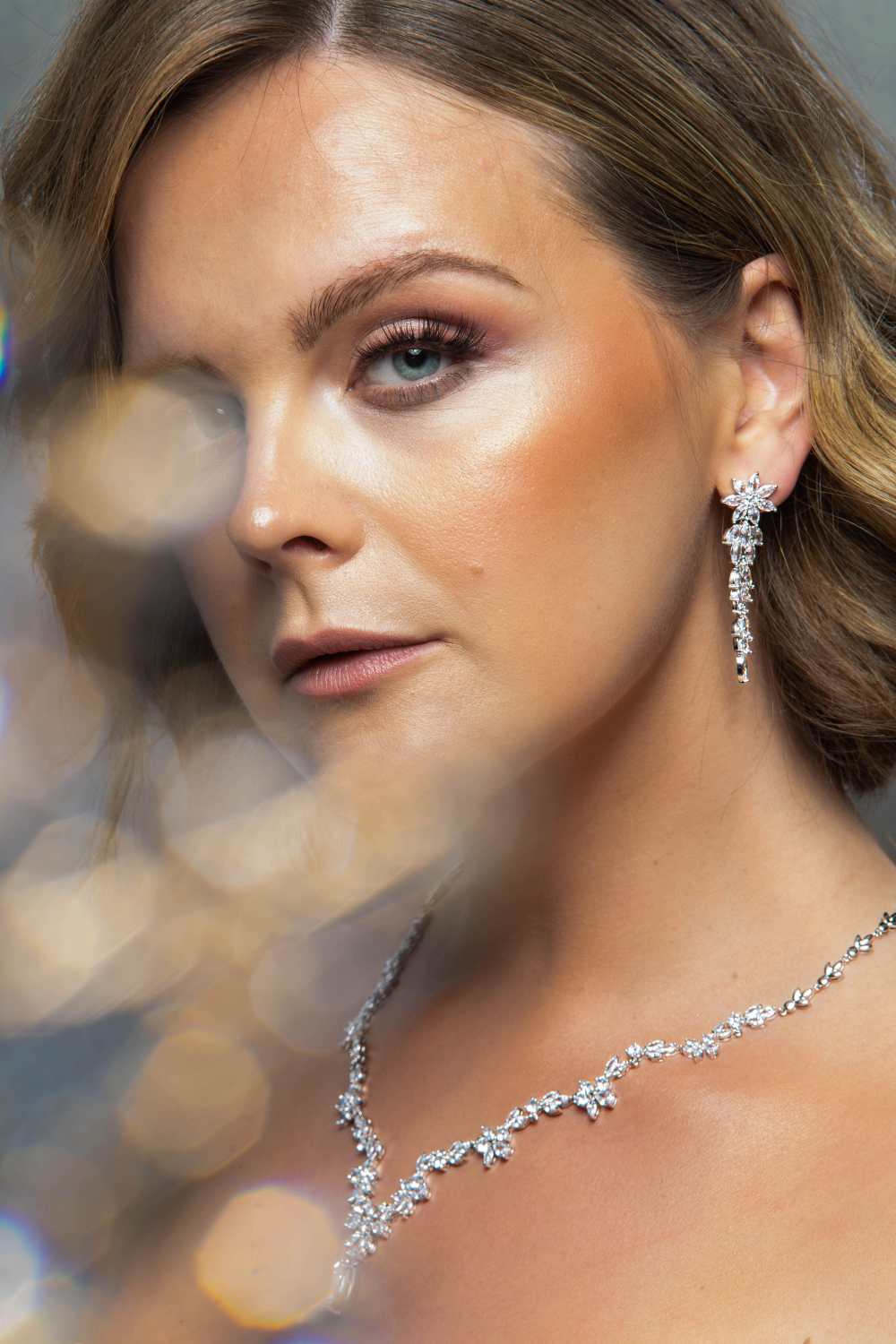 Woman wearing The Simone Set – close-up of floral bridal earrings and necklace with marquise and round-cut cubic zirconia stones